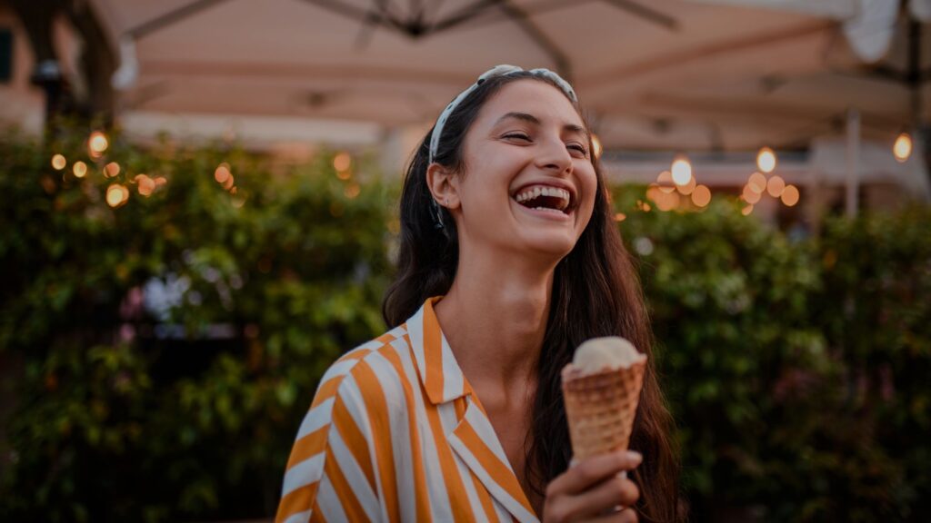 A young girl savoring a gelato cone in Italy, smiling and enjoying the treat.